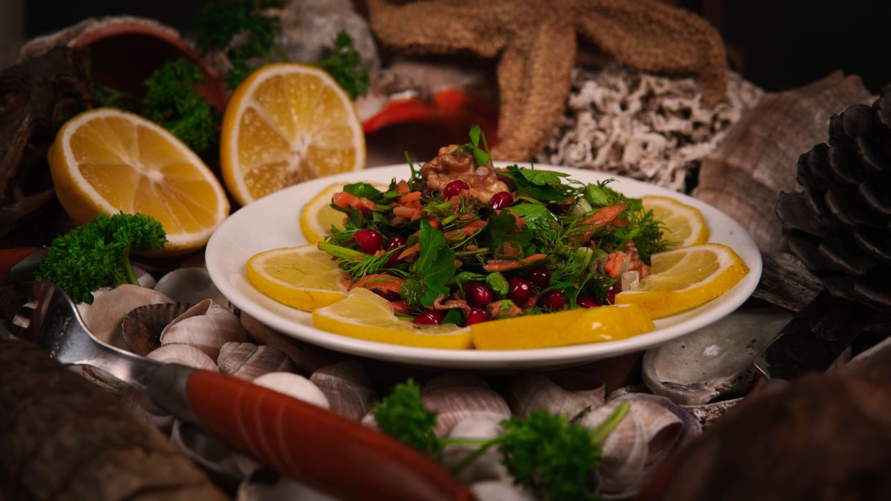 why-choose-us Vibrant salad with fresh herbs, walnuts, and lemon slices presented in a rustic setting.
