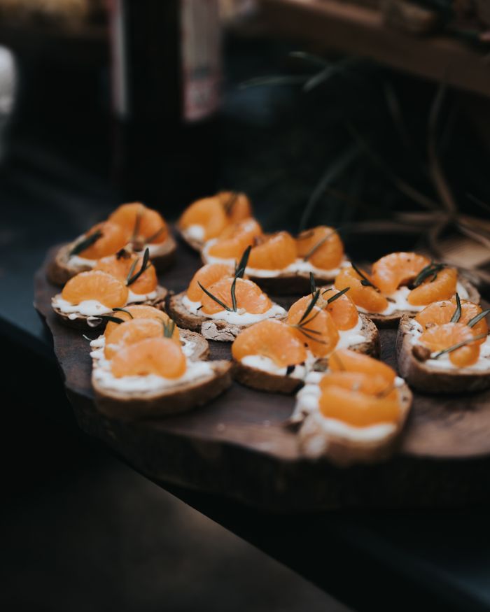 services-01 Delicious tangerine crostini with cream cheese and rosemary on a rustic wooden board.