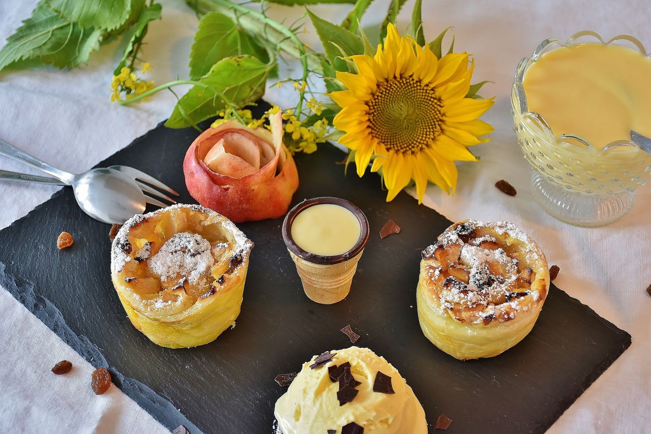 gallery-1 A cozy setup featuring apple strudel with vanilla sauce, ice cream, and a sunflower for a touch of brightness.