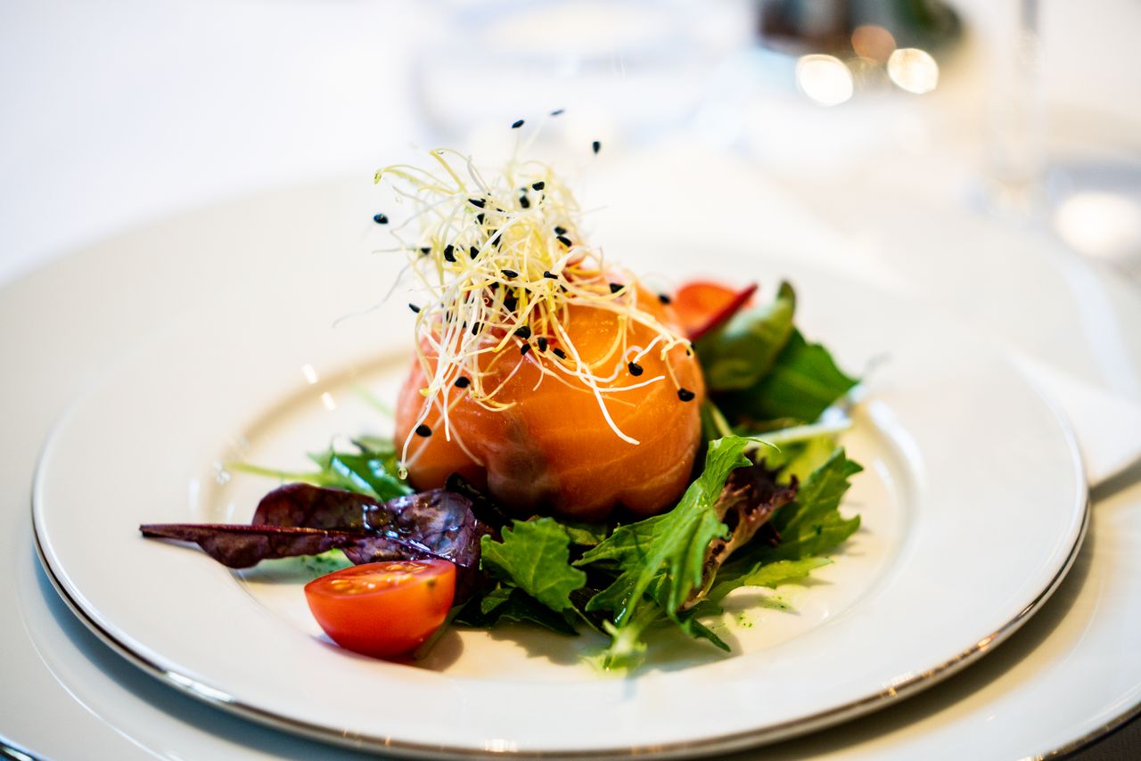 about-01 A gourmet salad featuring smoked salmon, fresh greens, and cherry tomatoes elegantly presented.