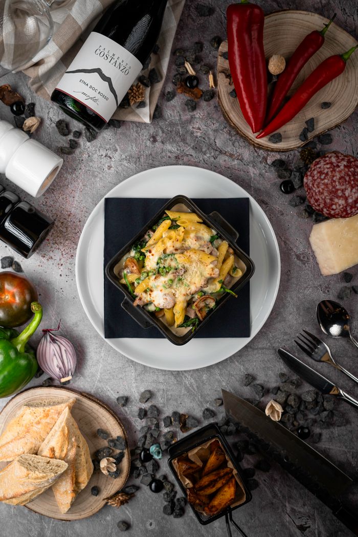 gallery-6 Top view of gourmet pasta with wine, peppers, and bread, perfect for a classy dining setting.
