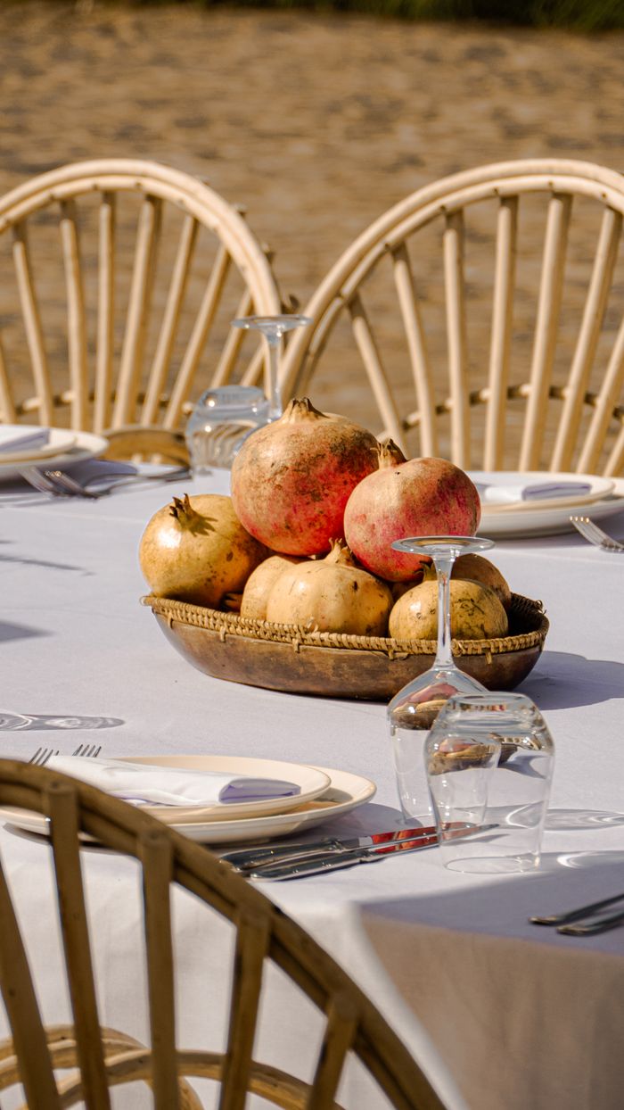 contact-img A beautifully set outdoor dining table with pomegranates as the centerpiece, perfect for a leisurely meal.