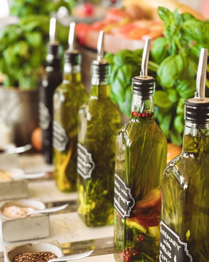 gallery-3 Close-up of gourmet infused olive oil bottles with fresh herbs and spices, perfect for Italian cuisine.